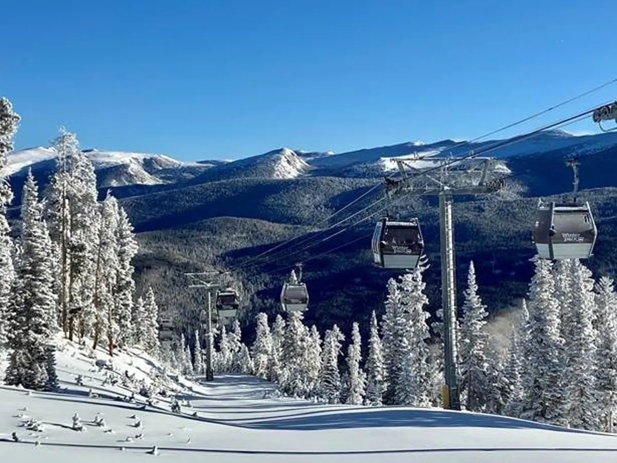 An exterior scene showing a ski lift ascending into the snow-covered mountains, surrounded by pine trees dusted with snow. The atmosphere is vibrant and adventurous, evoking the excitement of outdoor activities like skiing, snowboarding, and exploring mountain trails. The expansive mountain range in the background highlights the proximity to premier alpine recreation.